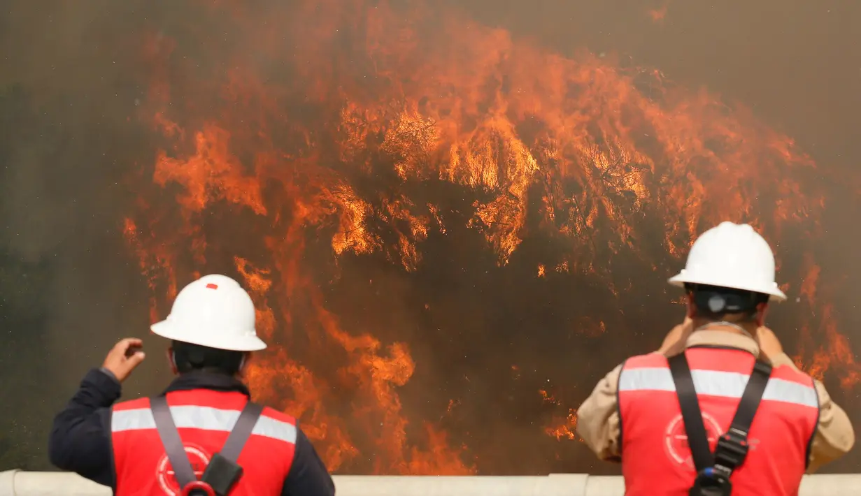 Dua orang petugas melihat kebakaran besar yang melanda kota pantai Valparaiso di Chile, Senin (2/1). Api menghanguskan sedikitnya 100 rumah dan mendorong evakuasi pada sekitar 400 orang. (REUTERS/Rodrigo Garrido)