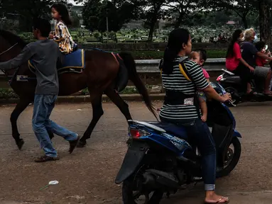 Seorang anak menaiki kuda di ruang kota Jalan Inpeksi Tanah Kusir, Jakarta, Senin (19/4/2021). Jalan Inpeksi Tanah Kusir ini menjadi salah satu tempat pilihan warga untuk menghabiskan waktu sembari menunggu berbuka puasa atau ngabuburit. (Liputan6.com/Johan Tallo)