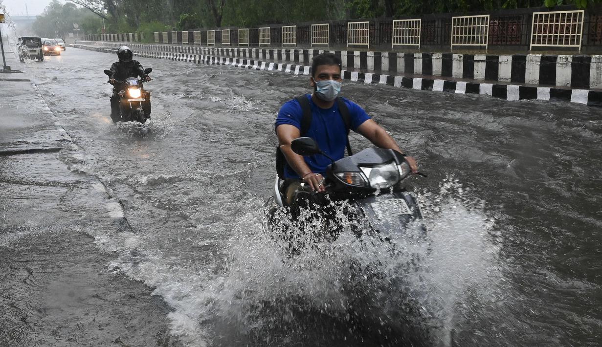 Pengendara motor melewati jalan yang tergenang air saat hujan lebat di New Delhi, India (1/9/2021). Stasiun cuaca mencatat curah hujan 112,1 mm dalam 24 jam yang berakhir pada hari Rabu pukul 08.30 waktu setempat. (AFP/Prakash Singh)