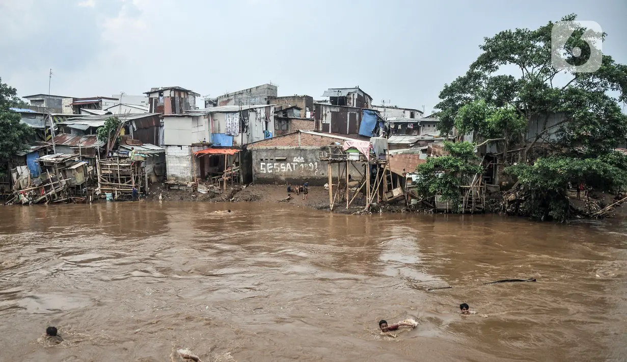 Anak-anak berenang di Kali Ciliwung yang meluap, Kebon Pala, Jatinegara, Jakarta Timur, Minggu (31/10/2021). Aliran Kali Ciliwung yang meluap akibat hujan di kawasan hulu dimanfaatkan anak-anak untuk berenang meski membahayakan keselamatan. (merdeka.com/Iqbal S. Nugroho)