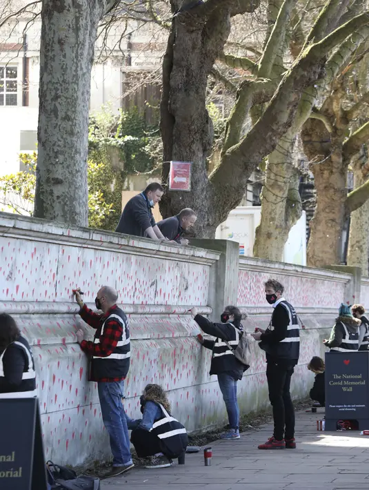 Gambar hati dilukis oleh seorang anggota keluarga yang berduka di Tembok Peringatan COVID-19, di seberang Gedung Parlemen, di London, Senin (29/3/2021). Mural hampir 150.000 lukisan hati itu untuk mengenang ribuan orang yang meninggal akibat virus corona di Inggris. (Lucianna Guerra/PA melalui AP)