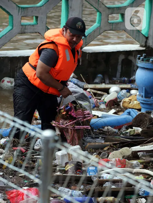 Petugas UPK Badan Air DLH Provinsi DKI Jakarta berjibaku membersihkan tumpukan sampah yang menghalangi aliran air Kali Mampang di Jalan Pejaten Raya, Jakarta, Sabtu (20/2/2021). Aliran air Kali Mapang di Jalan Pejaten Raya meluap akibat sumbatan tumpukan sampah. (Liputan6.com/Helmi Fithriansyah)