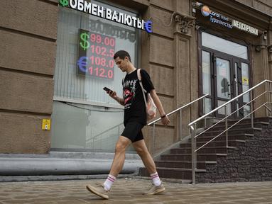 Seorang pria berjalan melewati kantor penukaran mata uang di Moskow, Rusia, Senin, 14 Agustus 2023.  (AP Photo/Alexander Zemlianichenko)