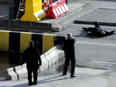 Polisi Turki mengarahkan senjata kepada seorang pria yang tergeletak di tanah, di luar kantor polisi di Gaziantep, Selasa (10/1). Pria itu ditembak mati, setelah sebelumnya mencoba memaksa masuk ke dalam kantor polisi dan menembak petugas. (AFP PHOTO/STR)