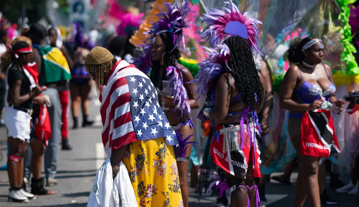 Sejumlah peserta berhenti di rute pawai saat ambil bagian dalam Parade West Indian Day di distrik Brooklyn, New York, Senin (3/9).  Parade untuk memperingati budaya dan sejarah Karibia tersebut digelar rutin setiap tahun. (AP Photo/Craig Ruttle)