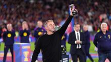Pelatih kepala Barcelona, Hansi Flick, mengangkat trofinya ke langit sambil merayakan kemenangan setelah mengalahkan Real Madrid 2-0 untuk menjuarai liga sepak bola Spanyol (La Liga) dengan tiga pertandingan tersisa, di Barcelona, Spanyol, Minggu, 10 Mei 2026. (AP Photo/Joan Mateu Parra)
