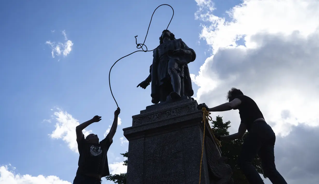 Mike Forcia (kiri) dan seorang pria mengikatkan tali pada leher patung Christopher Columbus saat sekelompok massa merobohkannya di Minnesota State Capitol, St. Paul, Minnesota, Amerika Serikat, Rabu (10/6/2020). (Evan Frost/Minnesota Public Radio via AP)