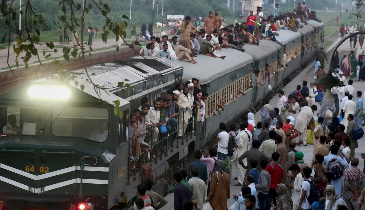 Sejumlah penumpang duduk di atas atap kereta saat mudik menuju kampung halaman untuk merayakan Idul Adha di Lahore, Pakistan, Sabtu (10/8/2019). Umat Islam di seluruh dunia merayakan Idul Adha yang identik dengan tradisi berkurban. (AP Photo/K.M. Chaudary)