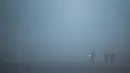 Seorang pria berlari di sepanjang jalan dalam kondisi berkabut akibat suhu dingin di New Delhi, Senin (30/12/2019). New Delhi, ibu kota India, saat ini mengalami musim dingin dengan hari dingin terpanjang dalam 22 tahun terakhir. (Photo by Jewel SAMAD / AFP)