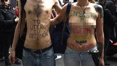 Sepasang demonstran bertelanjang dada saat menggelar aksi di Buenos Aires, Argentina (29/9). Dalam aksi ini badan mereka di cat dengan tulisan yang mengimbau bahwa rahim dan tubuh mereka kebebasan mereka. (AFP Photo/Juan Mabromata)