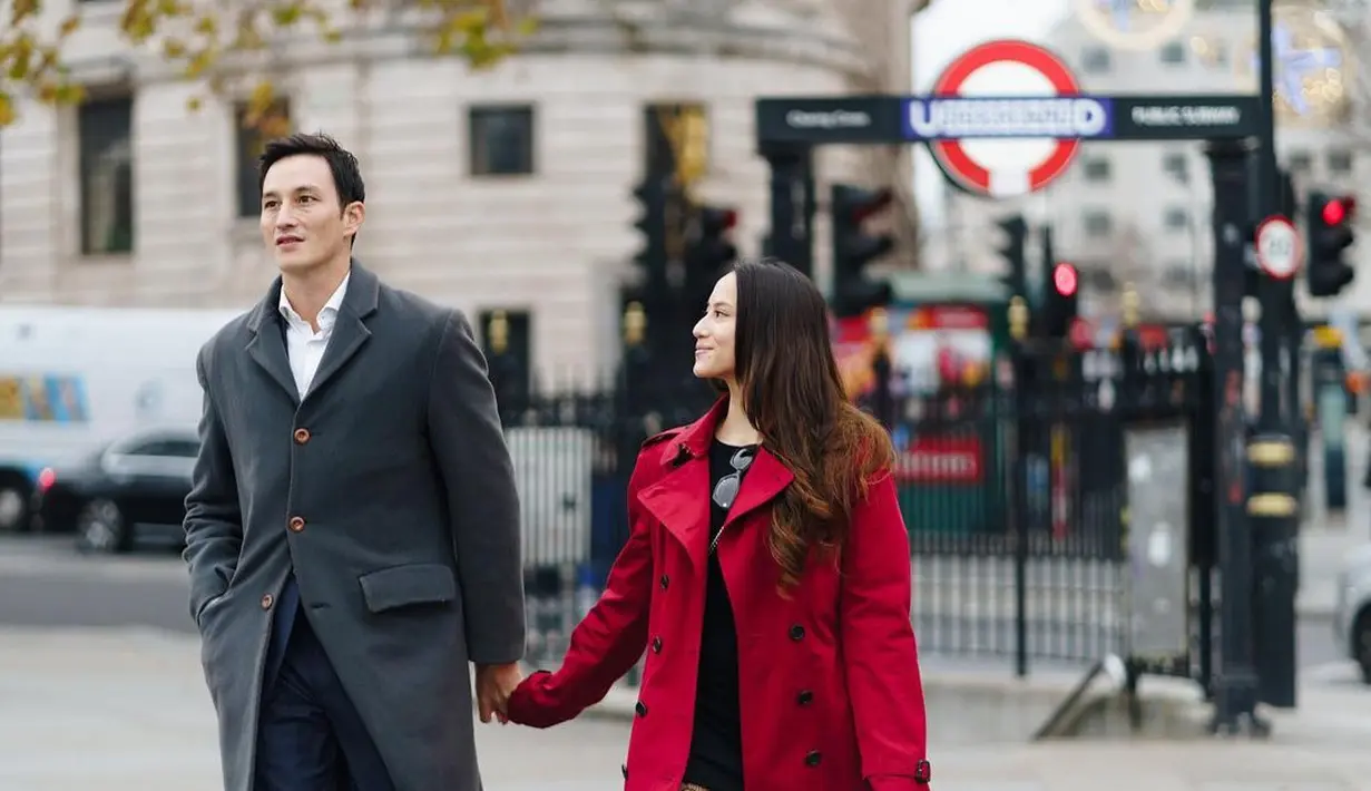 Di sesi prewedding yang dilakukan di London, Mike Lewis tampil keren dengan setelan jas Navy. Sementara Janisaa fashionable dengan dress pendek hitam dipadukan dengan stoking, high boots, dan coat merah. (instagram/mikelewis)
