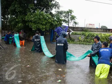 Petugas Suku Dinas Tata Air menarik selang pembuangan saat melakukan penyedotan air banjir di Jalan Gunung Sahari, Jakarta, Selasa (21/2). Hujan yang mengguyur sejak Selasa dinihari membuat sebagian wilayah di Jakarta banjir. (Liputan6.com/Faizal Fanani)