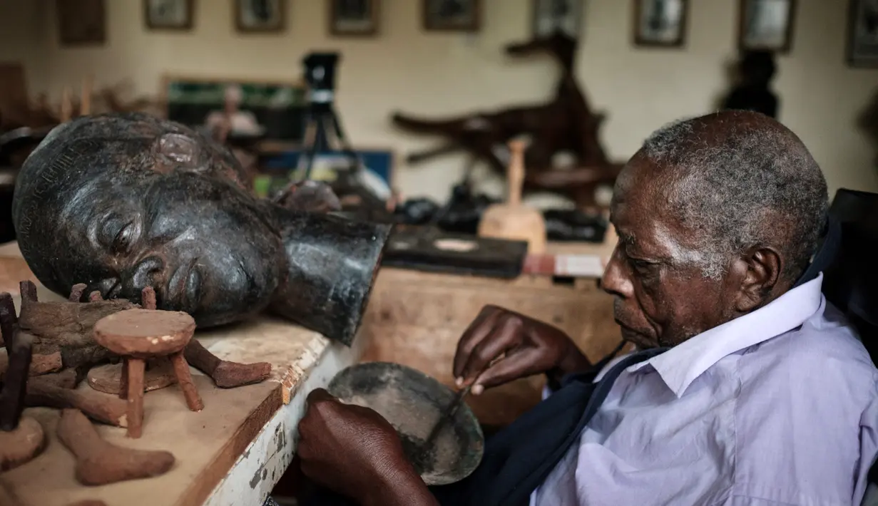 Edward Njenga bekerja memperbaiki patung karyanya yang berjuluk 'Women's Guild Member (2008)' di bengkelnya, Nairobi, Kenya, Senin (12/3).  Njenga lahir pada tahun 1922 dan menjadi pematung terkemuka. (AFP PHOTO/Yasuyoshi CHIBA)
