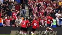 Che Adams dari Southampton, kiri kedua, merayakan mencetak gol pertama tim mereka dalam pertandingan melawan Manchester United, dengan rekan satu timnya Romain Perraud, kiri, dan Moussa Djenepo dan James Ward-Prowse di depan para penggemar selama pertandi