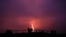 Warga melihat guguran lava pijar yang keluar dari gunung api Piton de la Fournaise atau Peak of the Furnace di Pulau Reunion, Samudera Hindia, Prancis, Selasa (13/8/2019). Letusan Piton de la Fournaise berlanjut hingga hari ketiga. (Richard BOUHET/AFP)