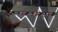 Pengunjung melintas dekat layar monitor pergerakan saham di gedung Bursa Efek Indonesia, Jakarta, Rabu (2/1). Indeks Harga Saham Gabungan (IHSG) pada pembukaan perdagangan saham 2019 menguat 10,4 poin atau 0,16% ke 6.204. (Liputan6.com/Angga Yuniar)