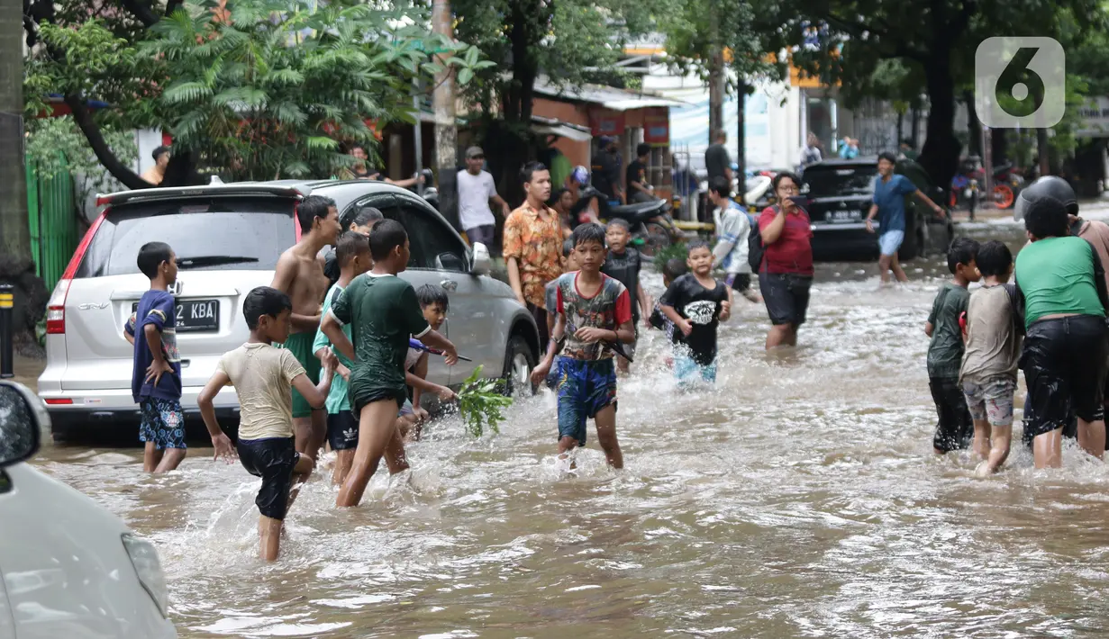 Anak anak bermain air di sebagian Jalan Bungur Besar Raya yang tergenang, Jakarta, Selasa (18/1/2022). Genangan air di sebagian Jalan Bungur Besar Raya dimanfaatkan anak-anak untuk bermain meski berbahaya. (Liputan6.com/Helmi Fithriansyah)