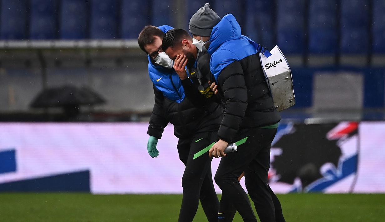 Bek Inter Milan, Danilo D'Ambrosio (tengah) dituntun ofisial tim meninggalkan lapangan akibat cedera dalam laga lanjutan Liga Italia 2020/21 pekan ke-16 melawan Sampdoria di Luigi Ferrari Stadium, Rabu (6/1/2021). Inter Milan kalah 1-2 dari Sampdoria. (AFP/Marco Bertorello)