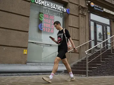 Seorang pria berjalan melewati kantor penukaran mata uang di Moskow, Rusia, Senin, 14 Agustus 2023.  (AP Photo/Alexander Zemlianichenko)