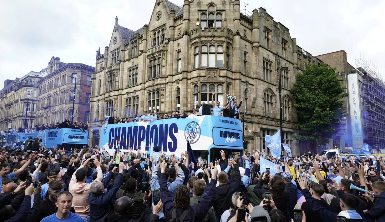Para pemain Manchester City menyapa para penggemar dari atas bus saat parade kemenangan Liga Inggris di Manchester, Inggris, 23 Mei 2022. (AP Photo/Jon Super)