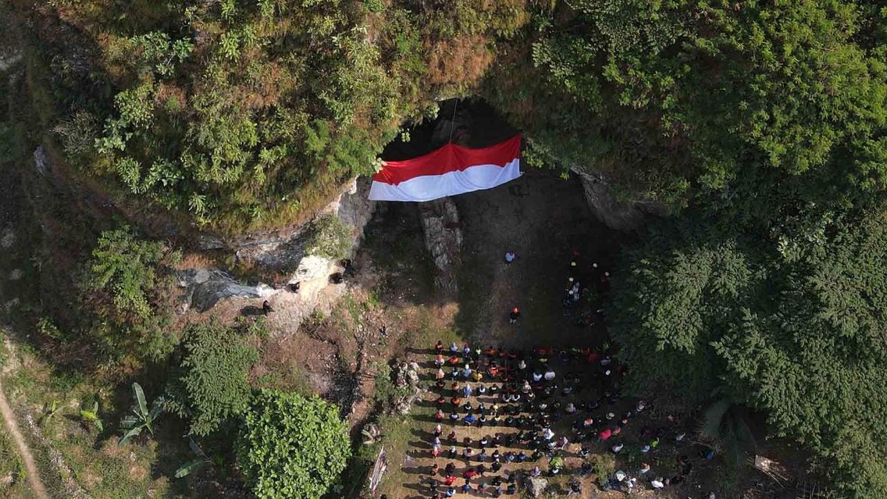 Foto udara memperlihatkan upacara pengibaran bendera merah putih pada HUT ke-78 Kemerdekaan RI di lokasi bekas tambang batu kapur Tebing Arpam, Gua Sigugula Karst Klapanunggal, Kabupaten Bogor, Jawa Barat, Kamis (17/8/2023).
