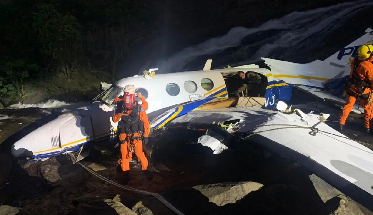 Petugas pemadam kebakaran berada di dekat puing-puing pesawat jatuh yang ditumpangi penyanyi Brasil Marilia Mendonca di Caratinga, pada 5 November 2021. Penyebab kecelakaan itu masih belum diketahui, dan pemerintah sedang memimpin penyelidikan. (Minas Gerais Fire Department / AFP)
