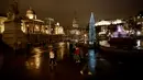 Orang-orang melewati pohon Natal setelah tradisi penyalaan lampu di Trafalgar Square, London, Kamis (6/12). Setiap tahun London mendapat pohon Natal dari Norwegia sebagai tanda terima kasih atas dukungan Inggris selama perang dunia II. (AP/Matt Dunham)