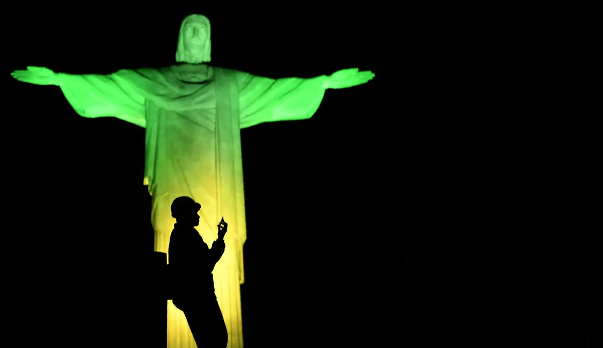 Dekorasi lighting patung Jesus oleh seniman Prancis Gaspare Di Caro beberapa menit sebelum pembukaan Olimpade Rio 2016 di Rio de Janeiro.(AFP/Jeff Pachoud)