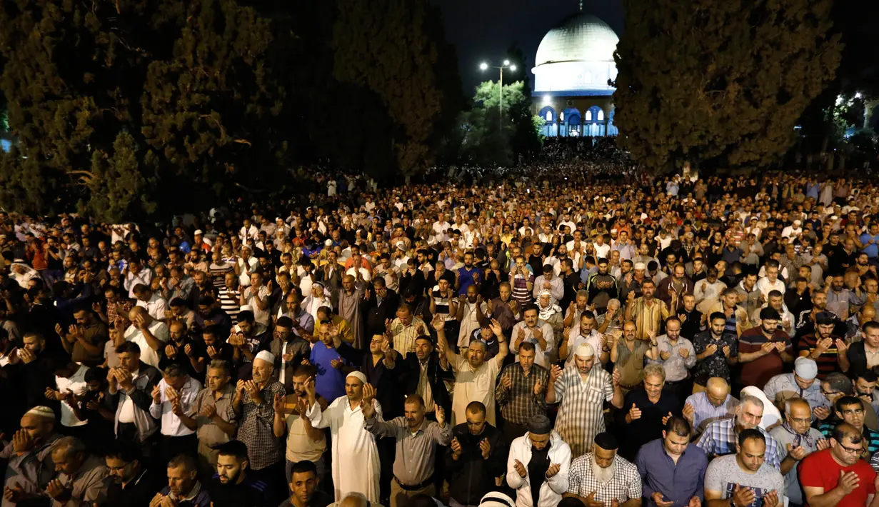Muslim Palestina memanjatkan doa sambil menunggu Lailatul Qadar di luar Dome of the Rock, kompleks masjid Al-Aqsa di Kota Tua Yerusalem, Senin (11/6). Umat Islam menanti malam lailatul qadar pada sepuluh hari terakhir Ramadan. (AFP/AHMAD GHARABLI)