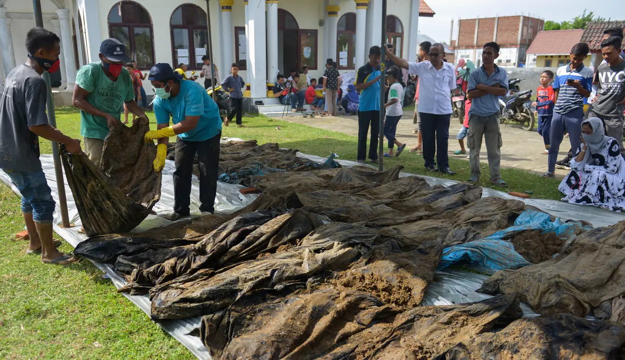 Warga melihat jenazah korban tsunami dan gempa 2004 di Kajhu, Aceh (19/12). Sekitar 30 jenazah korban tsunami Aceh dan gempa bumi ditemukan penduduk desa dekat lokasi konstruksi kompleks perumahan yang baru dibangun. (AFP Photo/Chaideer Mahyuddin)
