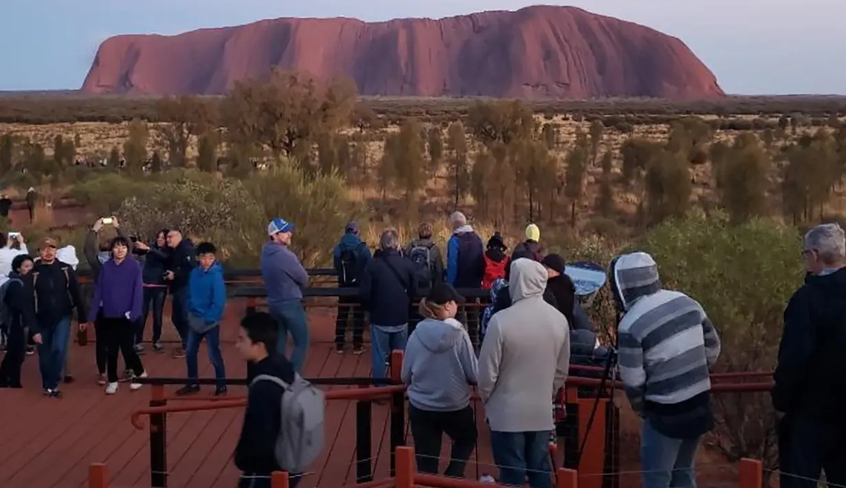 Selebaran yang diterima pada 10 Oktober 2019 memperlihatkan wisatawan memandangi Uluru di Utara Australia.  Pendakian di Batu Ayers tersebut akan dilarang mulai Oktober tahun ini, seiring dengan keinginan Anagu, suku asli Aborigin yang mendiami kawasan tersebut. (HO/ @koki_mel_aus/AFP)