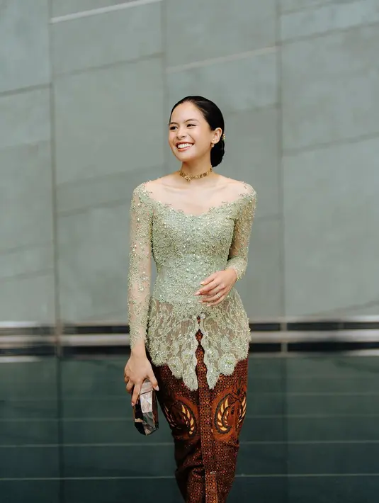 Ia memadukan kebaya hijau sage itu dengan kain batik cokelat tua dan clutch silver [@maudyayunda]