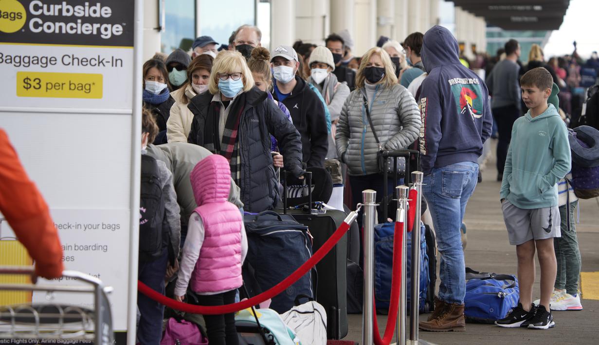 Penumpang antre untuk memeriksa bagasi mereka di tepi jalan terminal Bandara Internasional Denver di Denver, AS, Senin (3/1/2022). Badai musim dingin ditambah pandemi membuat frustrasi pelancong yang penerbangan pulang dari liburannya dibatalkan atau ditunda di awal tahun (AP Photo/David Zalubowski)