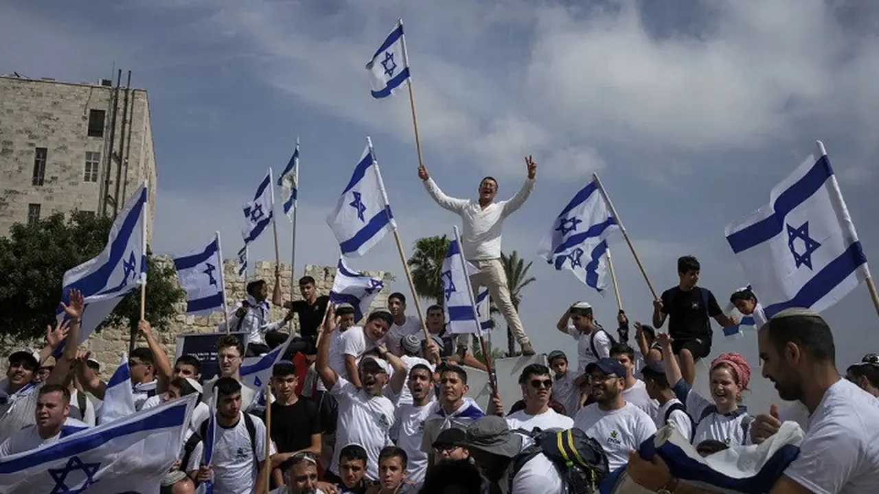 Warga Israel mengibarkan bendera nasional selama pawai peringatan Hari Yerusalem di luar Kota Tua Yerusalem pada Kamis (18/5/2023). (Dok. AP/Maya Alleruzzo)