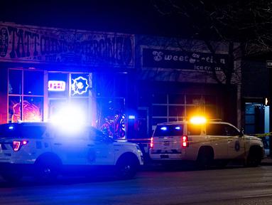 Kendaraan polisi berjaga di luar toko tato Sol Tribe di Broadway di mana dua wanita tewas ditembak dan seorang pria terluka di Denver, Colorado (27/12/2021). Polisi Denver sedang menyelidiki dua penembakan terpisah pada Senin malam. (Michael Ciaglo/Getty Images/AFP)