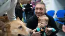 Pelatih menunjukkan kepada seorang anak laki-laki cara bermain dengan anjing Nike selama sesi terapi anjing di Kyiv, Ukraina, Kamis, 26 Oktober 2023. (AP Photo/Roman Hrytsyna)