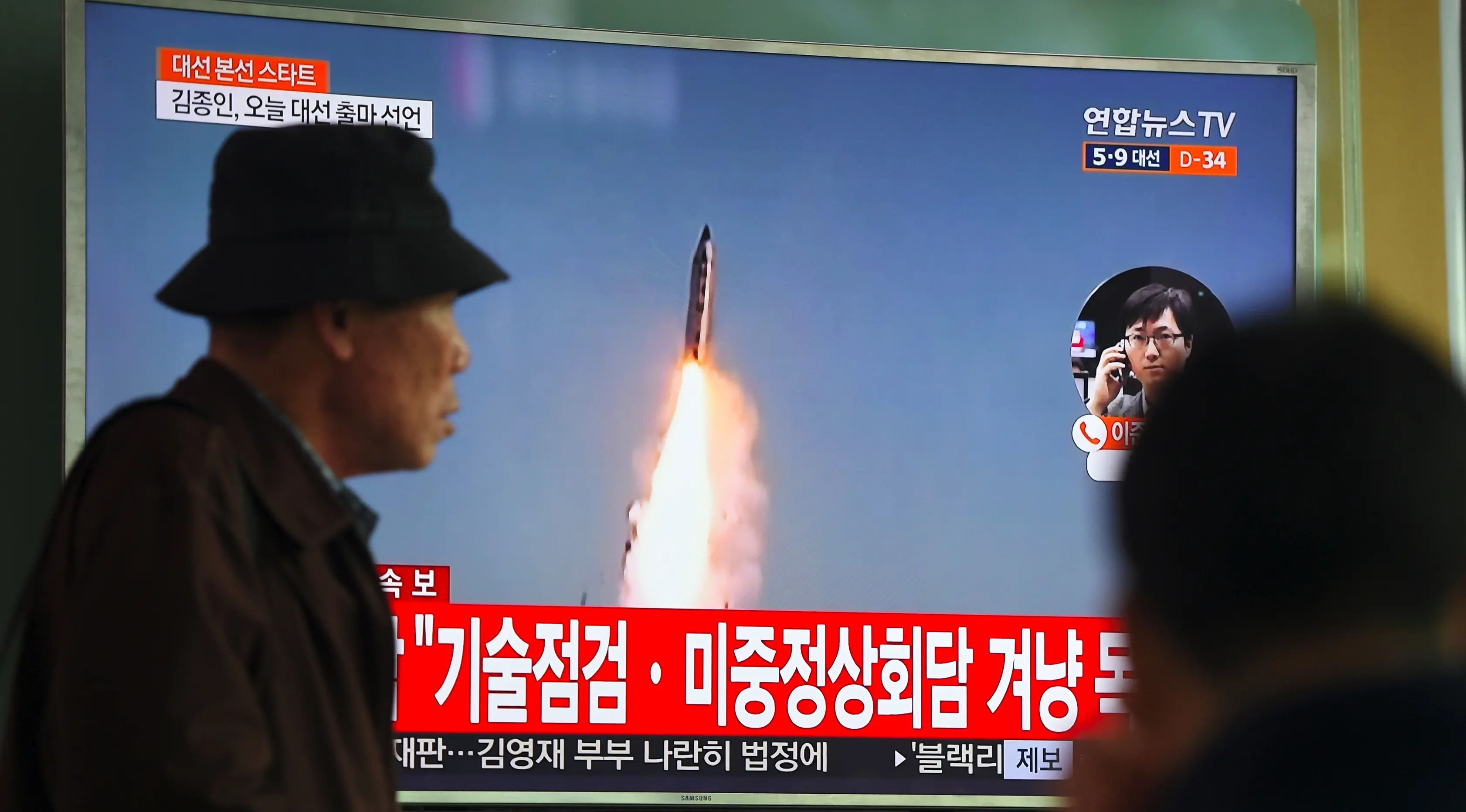 Seorang pria melewati layar televisi yang menyiarkan berita peluncuran rudal oleh Korea Utara (Korut), di sebuah stasiun kereta di Seoul, Korea Selatan, Selasa (5/4). Rudal itu ditembakkan dari wilayah timur Korut ke arah Laut Jepang. (JUNG Yeon-Je/AFP)