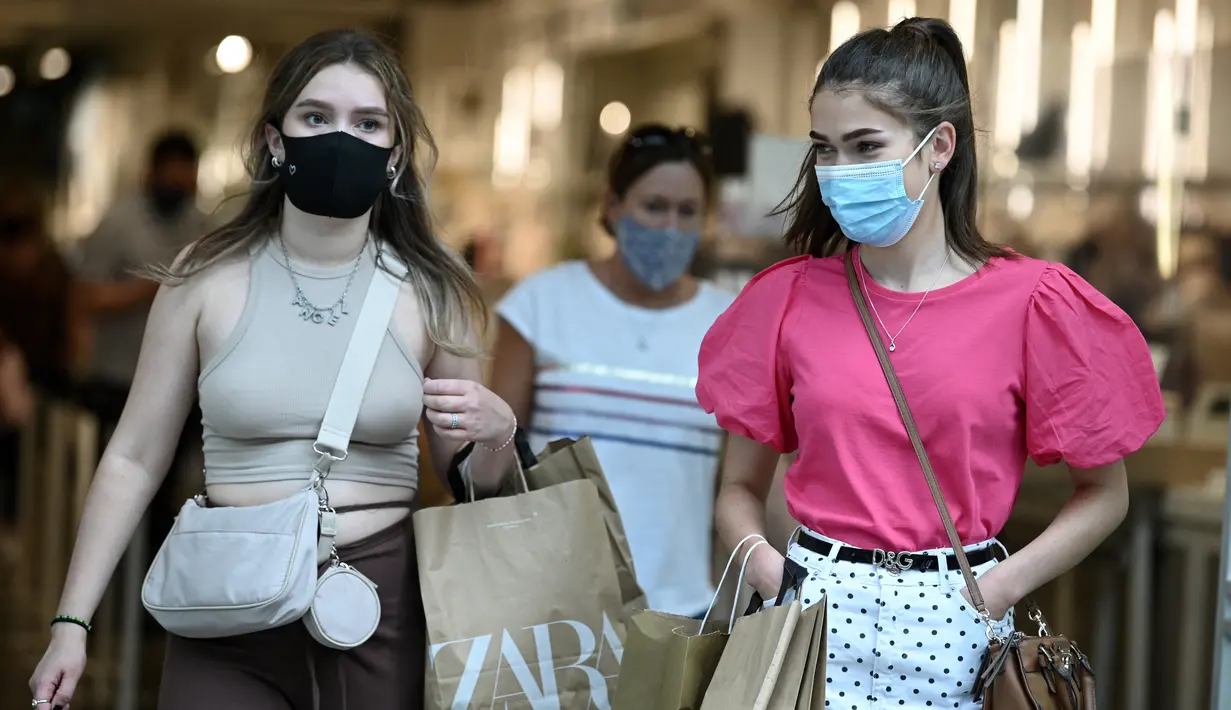 Pembelanja yang mengenakan masker meninggalkan toko di Oxford Street di pusat kota London, Senin (5/7/2021). PM Inggris Boris Johnson berencana mencabut sebagian besar pembatasan wilayah selama pandemi Covid-19, termasuk penggunaan masker dan jaga jarak mulai 19 Juli. (DANIEL LEAL-OLIVAS/AFP)