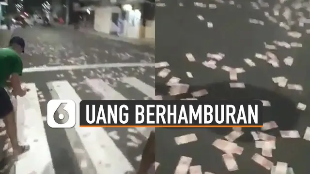 Terlihat momen ketika warga sedang memunguti uang-uang kertas yang berada di tengah jalan.