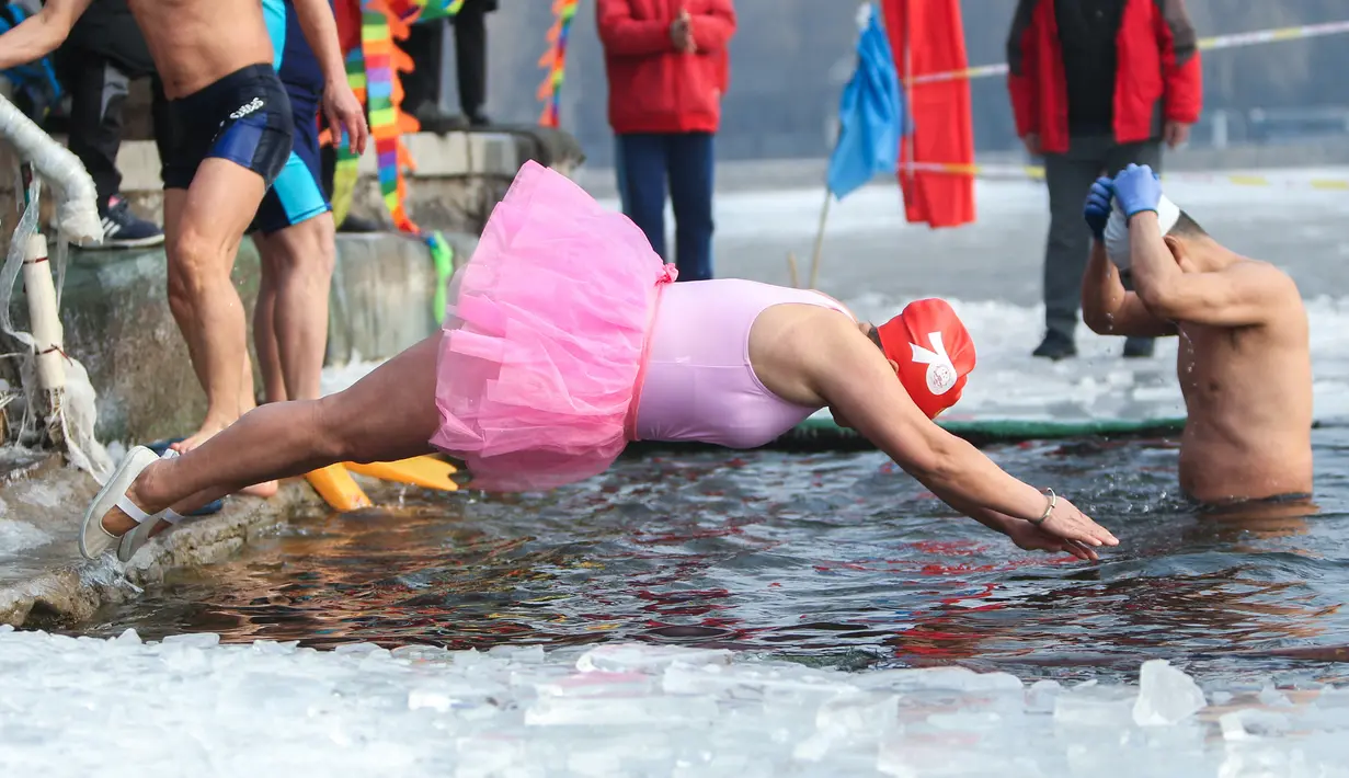 Seorang penggemar renang musim dingin menyelam ke danau yang sebagian beku di Shenyang, di provinsi Liaoning, China pada 25 Januari 2022. Berenang di musim dingin adalah kegiatan olahraga yang jarang dijumpai kecuali di beberapa negara dengan musim dingin yang cukup panjang. (STR/AFP)