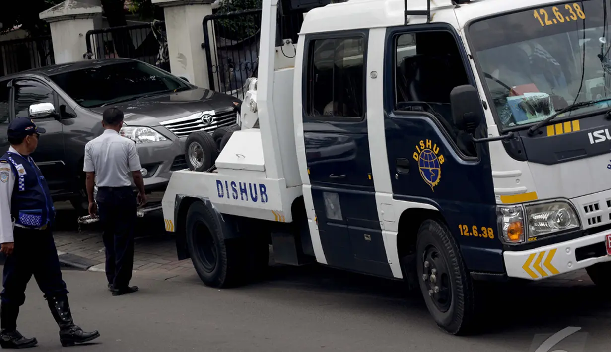 Penindakan parkir liar dengan melakukan derek oleh Dinas Perhubungan (Dishub) di depan sekolah SMA Kolese Kanisius Jakarta, Jalan Menteng Raya, Jakarta Pusat, Rabu (7/1/2015). (Liputan6.com/Faizal Fanani)