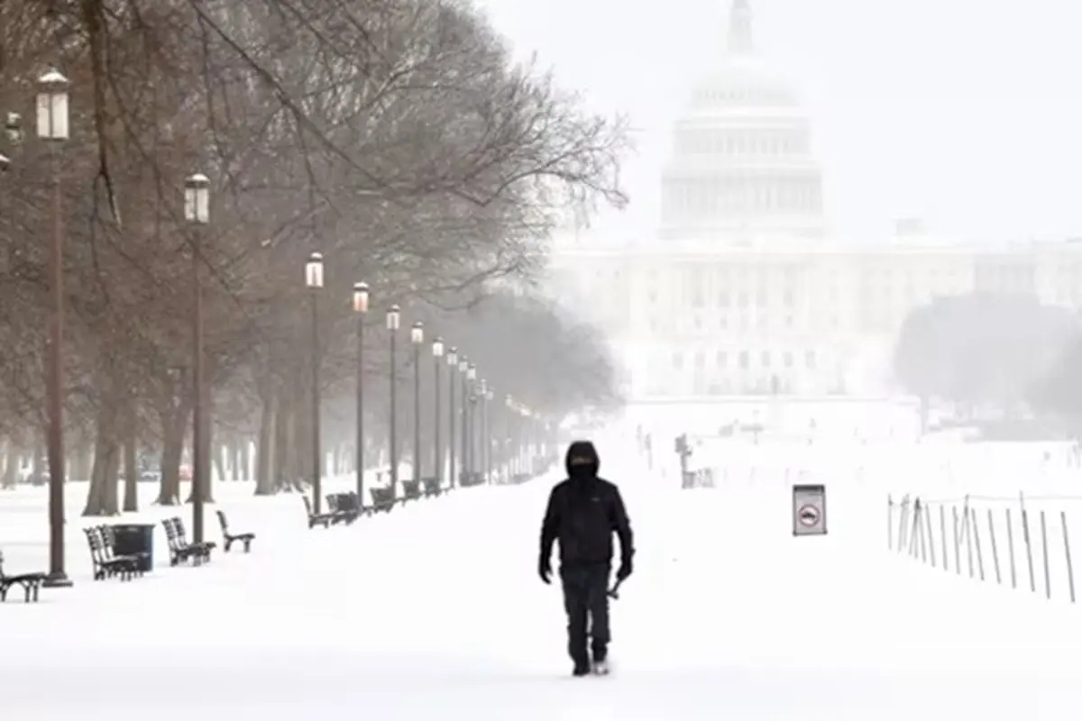 Seorang pria berjalan di kawasan National Mall saat salju turun di Washington, pada Minggu (25/1/2026).
