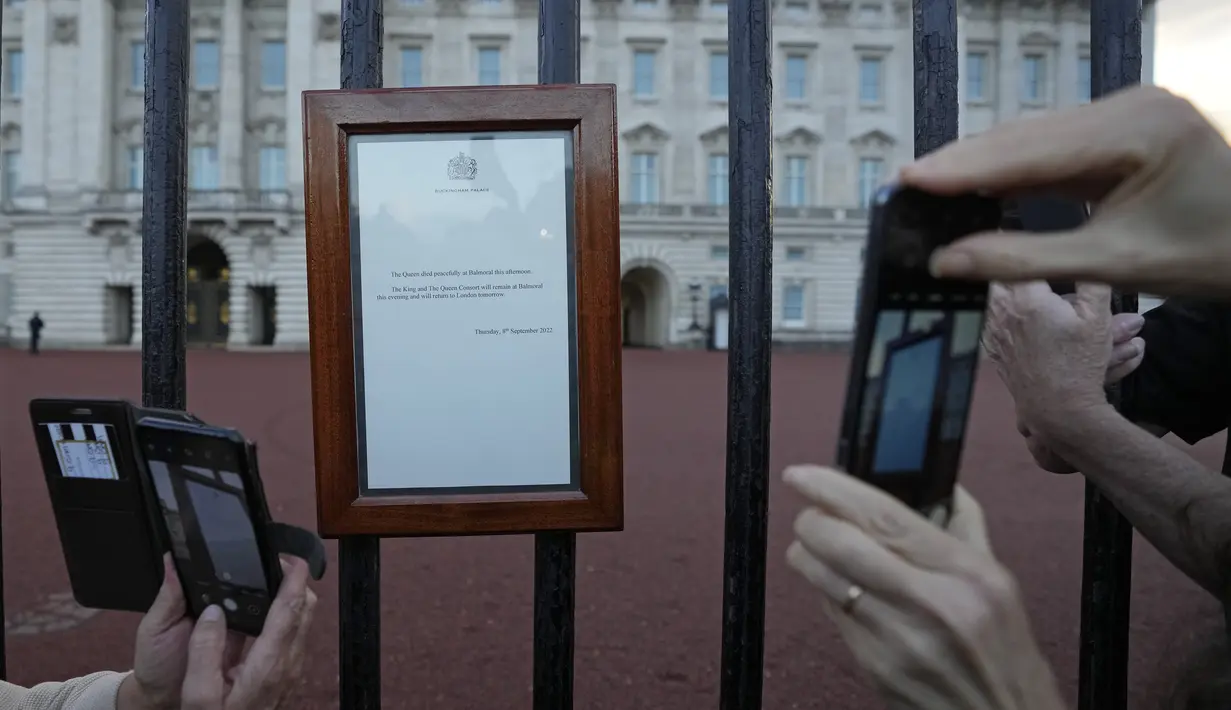 Orang-orang mengambil foto pengumuman tentang kematian Ratu Elizabeth II yang ditampilkan di gerbang Istana Buckingham di London, Kamis, 8 September 2022. Masyarakat berkumpul di luar Istana Buckingham saat berita Ratu Elizabeth II meninggal dunia tersiar. (AP Photo/Frank Augstein)