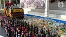 Petugas dengan alat berat menghancurkan botol minuman keras (miras) saat pemusnahan Miras dan barang bukti narkotika di Mapolrestabes Semarang, Jumat (20/12/2019). Pemusnahan barang bukti narkoba berupa sabu, inex dan pil koplo serta 5450 botol dan 140 liter ciu. (Liputan6.com/Gholib)
