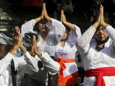 Umat Hindu Bali berdoa saat merayakan Hari Raya Kuningan di Pura Sakenan, Bali, Sabtu (18/6/2022). Kuningan menandai hari terakhir perayaan Galungan, salah satu upacara keagamaan terbesar umat Hindu di Bali. (AP Photo/Firdia Lisnawati)