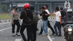 Polisi berpakaian kaus putih mengamankan seseorang yang dicurigai terlibat kericuhan di kawasan Tugu Tani, Jakarta, Selasa (13/10/2020). Sejumlah pemuda diamankan polisi karena dicurigai terlibat kericuhan di kawasan Tugu Tani. (Liputan6.com/Helmi Fithriansyah)