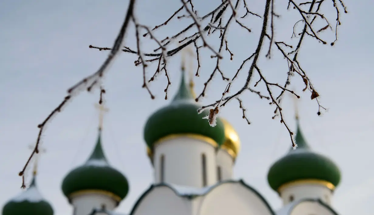 Ranting pohon yang dihinggapi salju dengan latar belakang kubah gereja di desa wisata Suzdal, Rusia (23/1). Tempat yang tenang dan menawan ini memiliki jalan tidak beraspal dengan gereja berkubah warna-warni. (AFP Photo/Mladen Antonov)