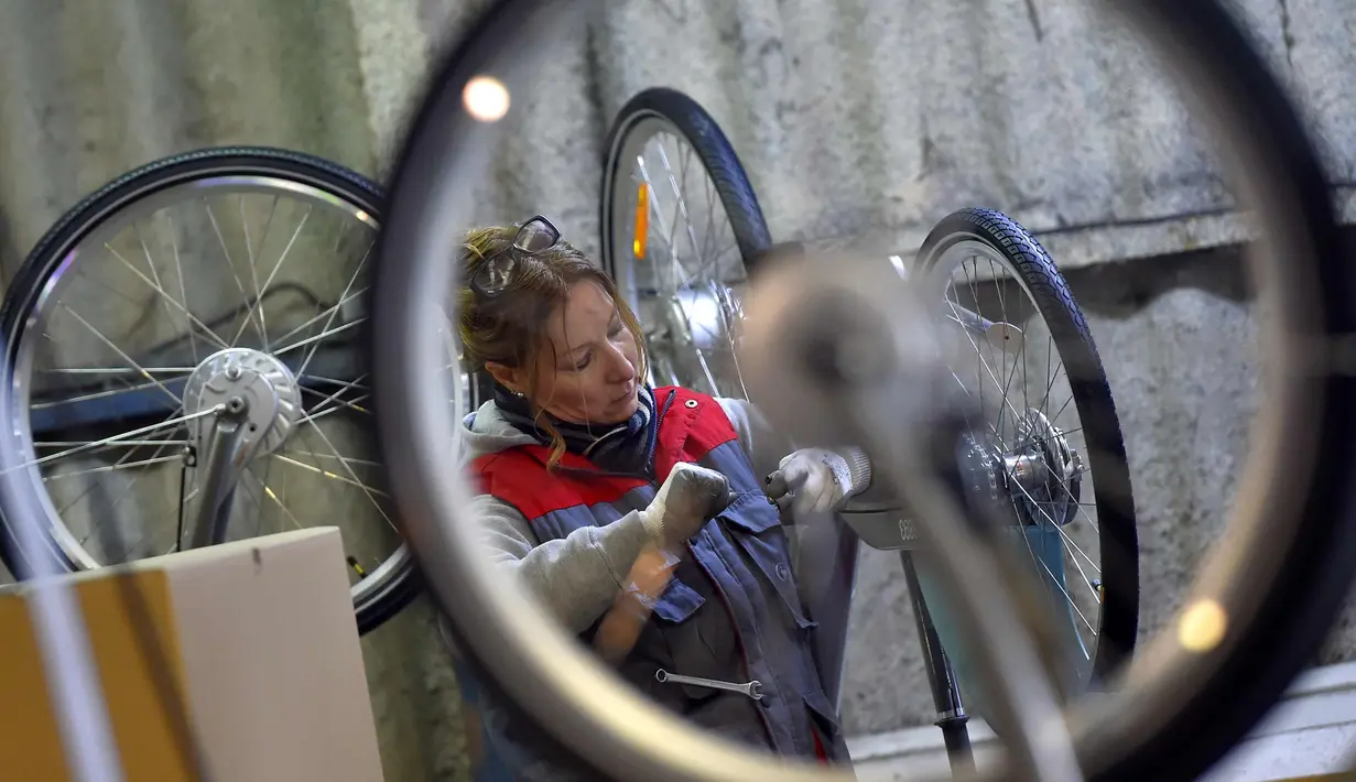 Seorang pekerja memasangkan pedal sepeda listrik Velib di pabrik Arcade Cycle di Paris, Prancis, (19/12). Sepeda yang dibuat dipabrik ini untuk disewakan di kota-kota di seluruh dunia khususnya di Prancis. (AFP Photo/Loic Venance)