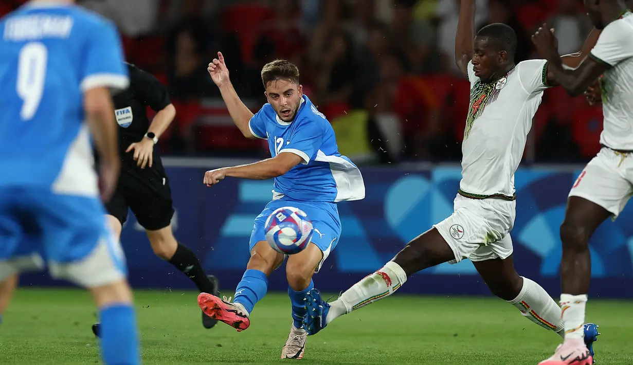 Bek Israel #12 Noam Ben Harosh menendang bola melewati bek Mali #04 Mamadou Tounkara pertandingan Grup D Olimpiade 2024 di Stadion Parc des Princes, Prancis, Kamis (25/7/2024) dini hari WIB. (FRANCK FIFE / AFP)