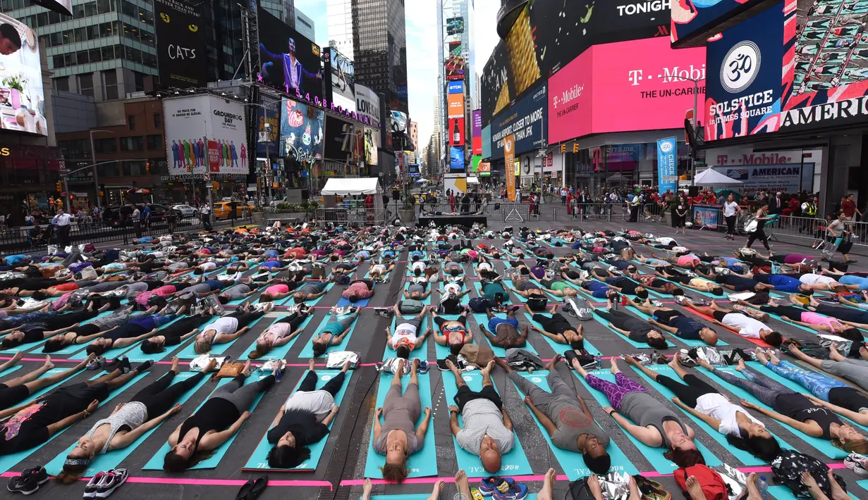 Warga ambil bagian berlatih yoga bersama di kawasan Times Square, New York pada 'Summer Solstice' atau hari dengan siang terpanjang di musim panas, Rabu (21/6). Acara itu menandai Hari Yoga Internasional yang jatuh pada 21 Juni. (TIMOTHY A. CLARY/AFP)